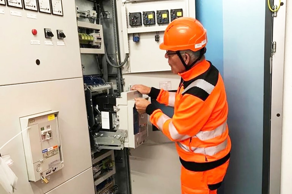 Technicien en vêtements haute visibilité travaillant sur une armoire électrique industrielle