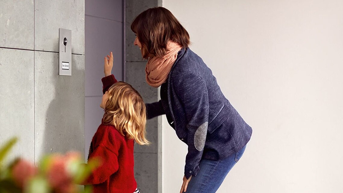 Adulte et enfant interagissant avec un interphone domestique moderne sur un mur