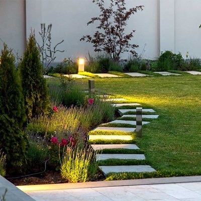 Jardin avec pré vert et chemin éclairé