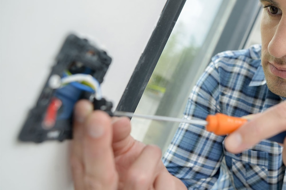 Homme qui raccorde une prise de courant avec un tournevis