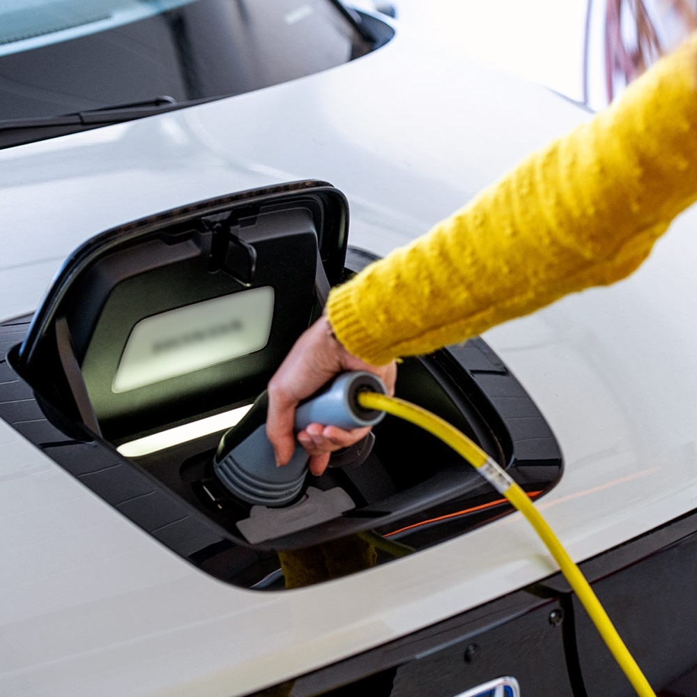 Zoom sur bras d'une femme rechargeant son véhicule électrique sur une borne de recharge witty de Hager