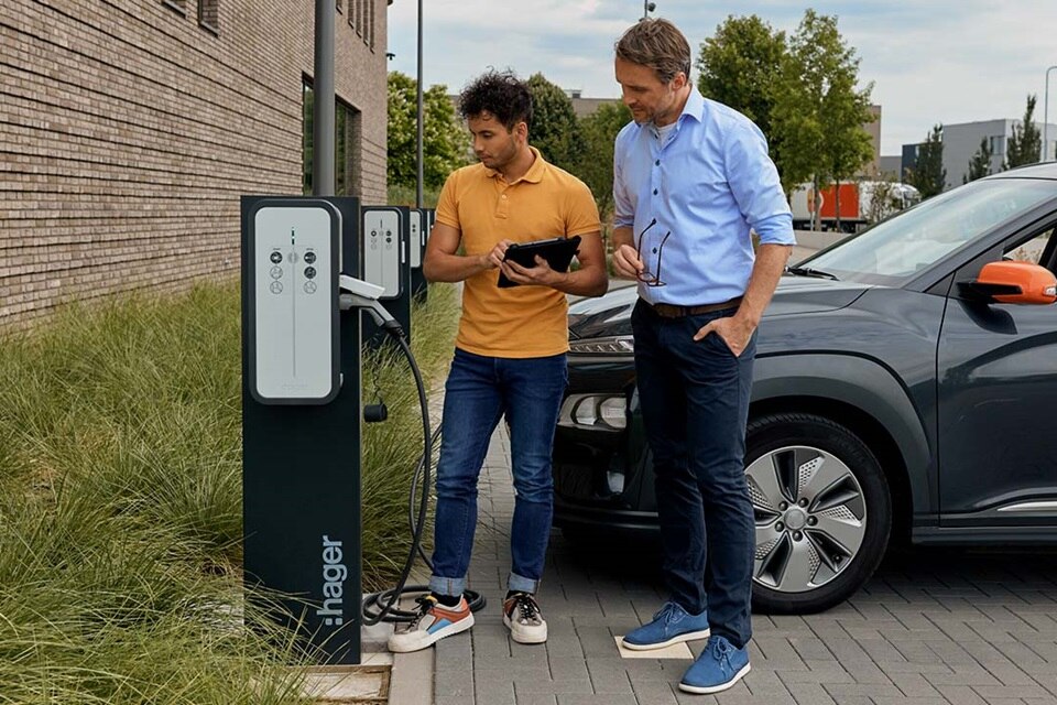 deux hommes sur un parking d'entreprise devant une borne witty park de Hager équipée du nouveau disjoncteur diférentiel 4PP
