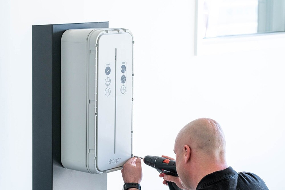 Electricien Hager qui installe une borne de recharge pour véhicules électriques witty de Hager