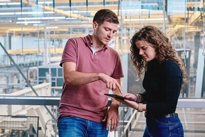 Un homme et une femme, collaborateurs  Hager qui échangent autour d'une tablette dans une usine du groupe