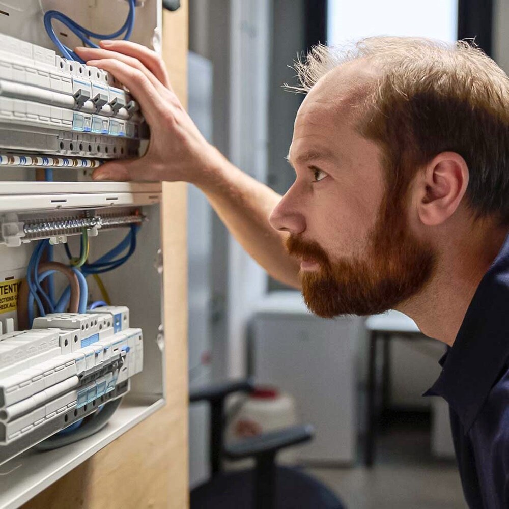 électricien qui met en place des éléments modulaires  Hager dans une armoire électrique