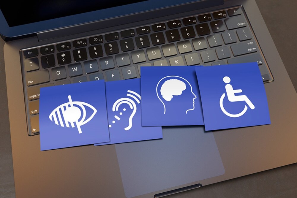 cartes bleues et blanches représentant différents handicaps posées sur un clavier d'ordinateur portable