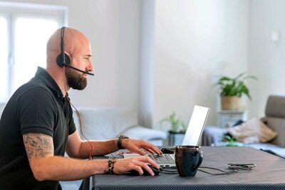 Installateur suivant une formation digitale proposée par Hager dans son salon devant son PC