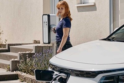 Femme qui branche sa voiture sur une borne de recharge électrique witty de Hager