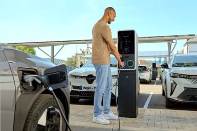 Sur un parking doté de bornes de recharge witty park 2 de Hager, un homme recharge son véhicule électrique.