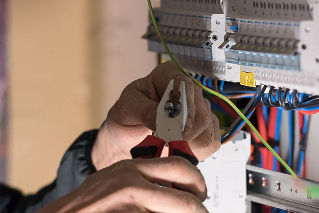 Main d’un électricien travaillant sur les raccordements d’un tableau