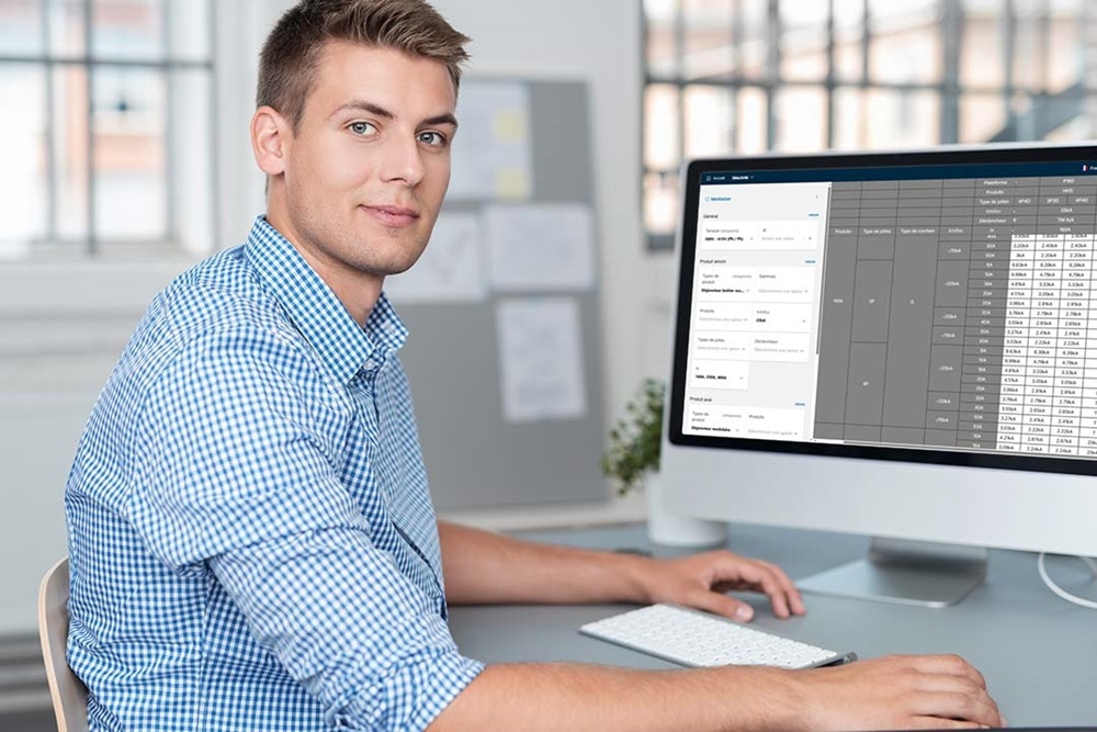 Homme qui travaille sur un ordinateur à son bureau avec l'écran ouvert sur la webapp HPC (Hager Protection Coordination)