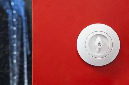 appareillage mural 1930 de Hager, plaque et interrupteur blanc sur mur rouge