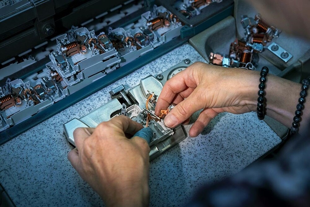 main d'ouvrier au montage de composants pour tableaux électriques dans l'usine Hager d'Obernai (67)