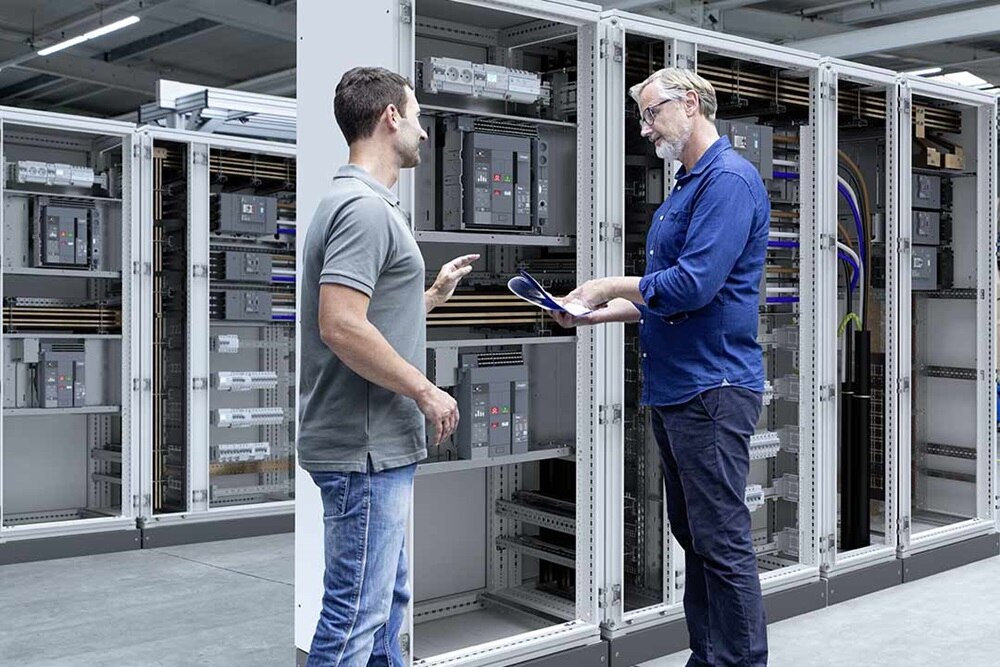 2 électriciens discutant devant une armoire Hager au sujet de disjoncteurs ACB