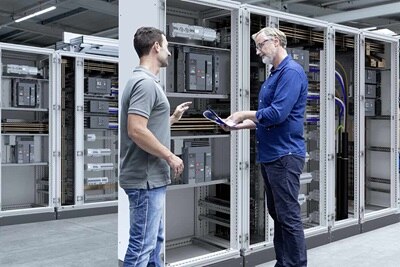 2 électriciens discutant devant une armoire Hager au sujet de disjoncteurs ACB