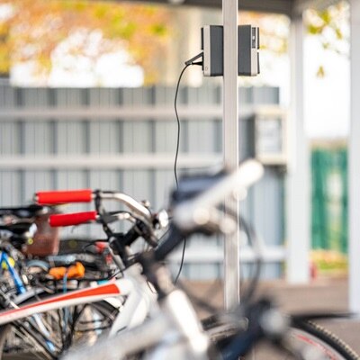 Prise witty de Hager pour les trottinettes, vélos, scooters et autos, parc de vélos électriques branchés sur un parking d'entreprise en extérieur sous auvent