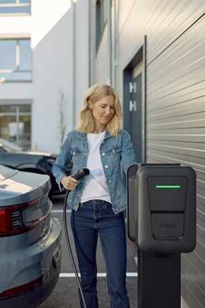 Femme qui recharge sa voiture sur un parking privé avec une borne witty pro de Hager