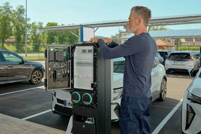 Un électricien installe une borne de recharge witty park 2 de Hager sur un parking.