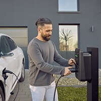 Homme qui branche son véhicule à la borne de recharge spirituelle plus de Hager