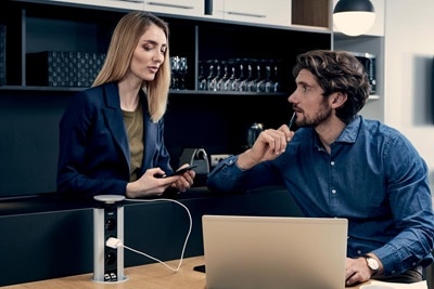 Couple, dans la salle de pause, utilisant une colonnette pour charger le PC portable