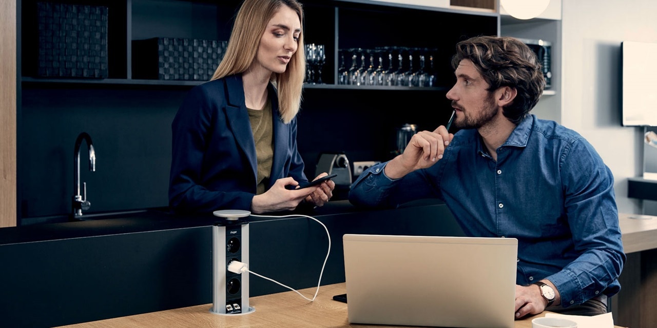 Couple, dans la salle de pause, utilisant une colonnette pour charger le PC portable
