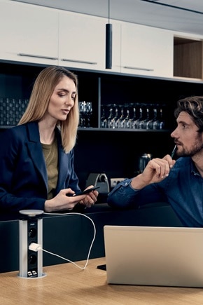 Couple, dans la salle de pause, utilisant une colonnette pour charger le PC portable