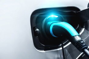 Gros plan sur une prise de recharge branchée sur un véhicule électrique blanc