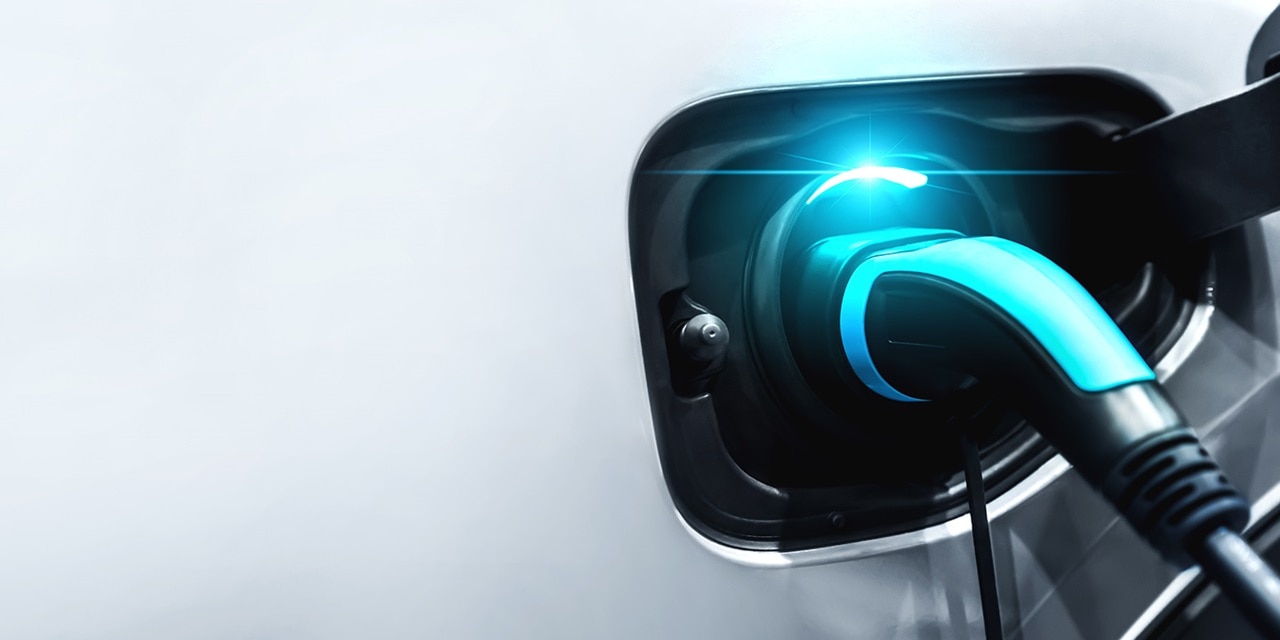 Gros plan sur une prise de recharge branchée sur un véhicule électrique blanc