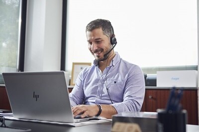 Homme au bureau avec un casque fait de l'assistance téléphonique et saisit sur un ordinateur portable