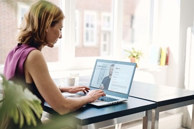 Femme au bureau devant un ordinateur portable en train de se connecter à son espace client sur le site Hager