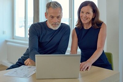 Couple devant un ordinateur portable au coin d'un bureau