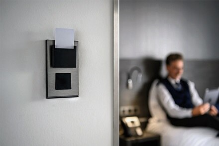 appareillage mural gallery de Hager, finition natural alu, fonction interrupteur  équipé de la bande lumineuse, à l’entrée d’une chambre d'hôtel.