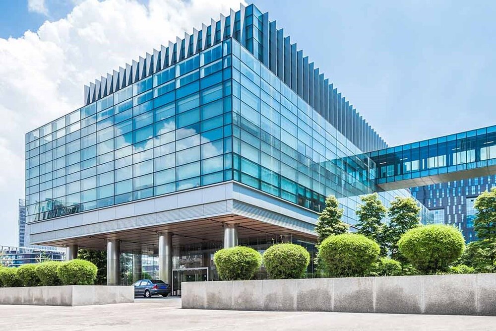 Bâtiment tertiaire aux fenêtres vitrées avec esplanade en béton et verdure