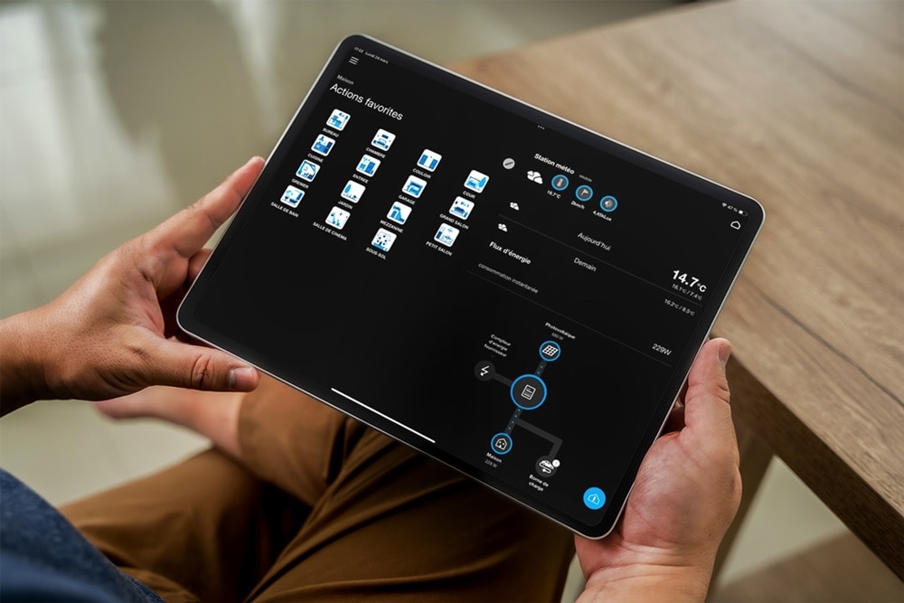 Homme tenant un iPad qui consulte domovea de Hager pour piloter les automatismes de sa maison