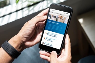 Homme utilisant help.hager le support d'aide pour les pro, pour l'installation de produits, l'aide sur nos logiciels, le chiffrage, etc. sur un smartphone