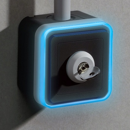 appareillage mural cubyko de Hager, boîte simple grise, collerette lumineuse à LED bleues 230V allumée, interrupteur à clé 3 positions associable Gris mur intérieur béton, pièce sombre