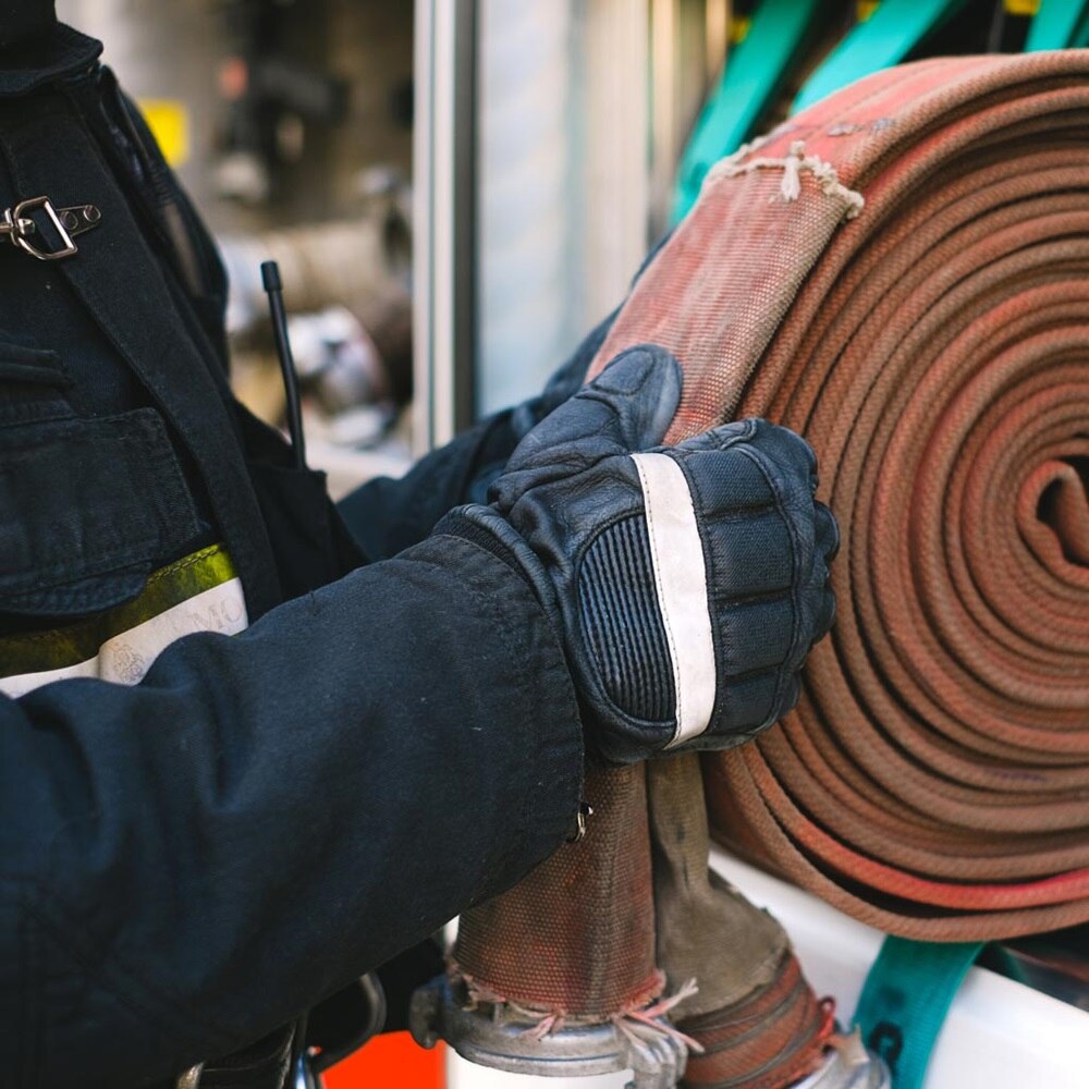 pompier déroulant une lance à incendie