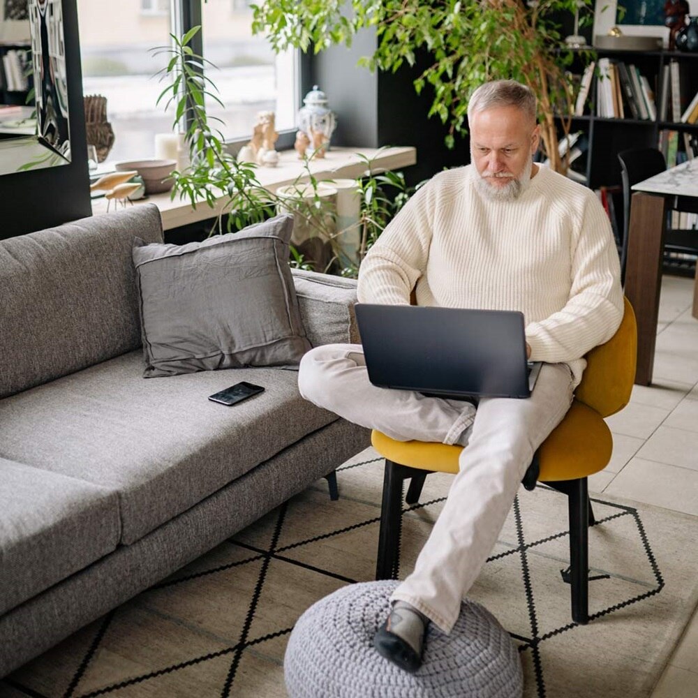 Senior relax qui surfe sur son ordinateur portable dans son intérieur confortable
