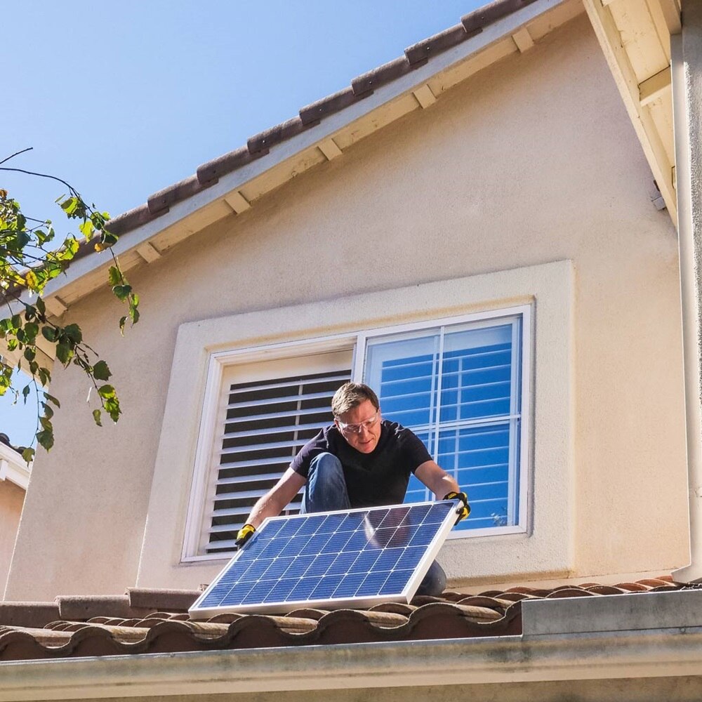 Homme qui installe un panneau solaire sur le toit de sa maison