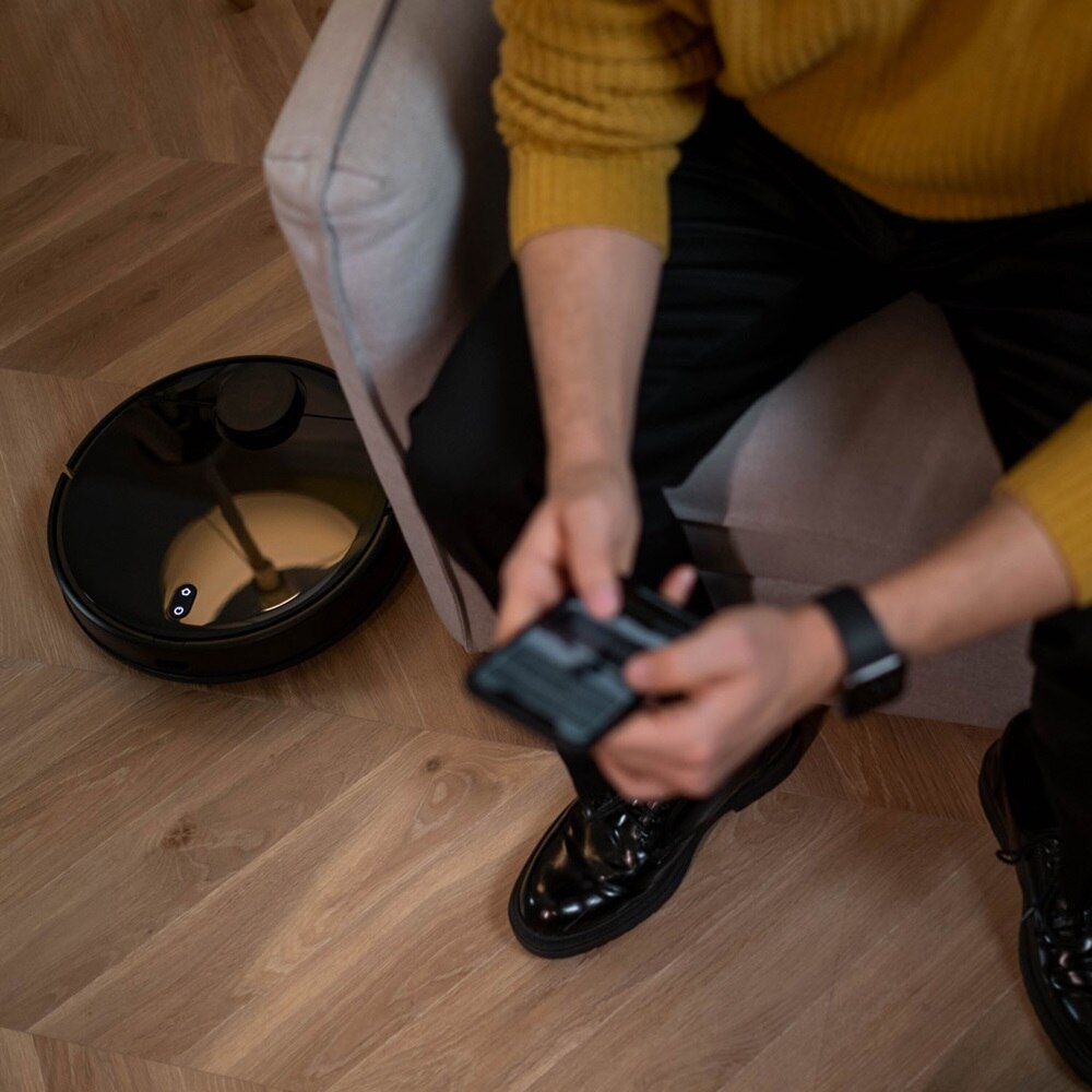 Homme qui programme son robot connecté à l'aide de son smartphone