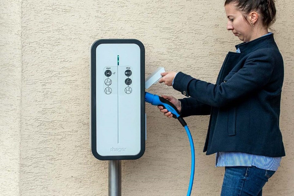 Femme qui branche son câble sur une borne de recharge witty de Hager