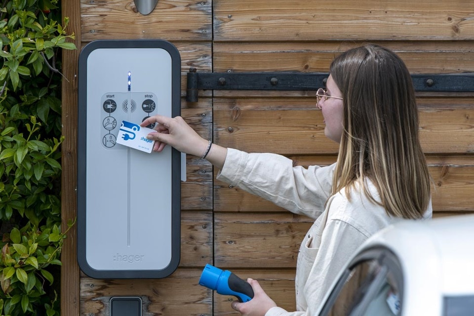 Utilisatrice passant son badge d'authentification RFID sur le lecteur RFID de la borne witty de Hager, borne de recharge, badge utilisateur