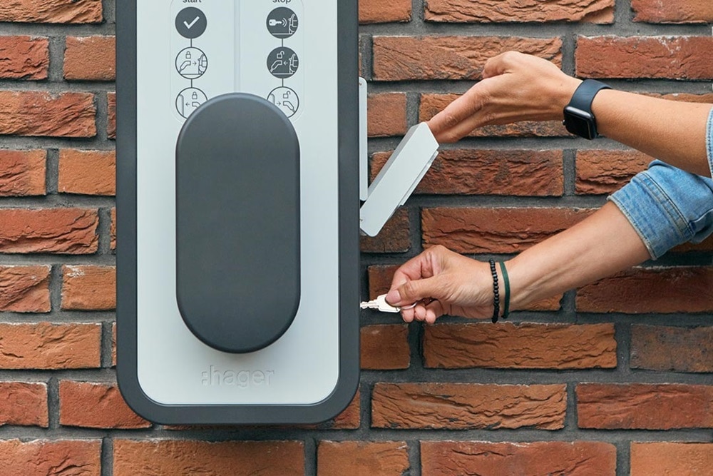 Utilisatrice de la borne witty de Hager qui insère la clé dans une borne pour verrouiller ou déverrouiller l'accès pour la recharge de véhicules électriques. système de sécurité, accès limité