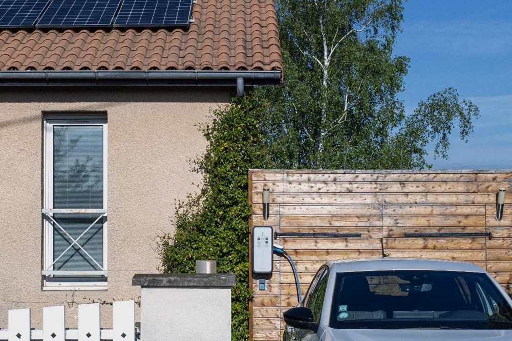 Maison individuelle sous le soleil équipée en panneaux solaires et d'une borne de recharge witty solar de Hager pour charger un véhicule électrique avec la production d'énergie du toit