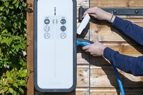 Mains en train de brancher un câble de recharge pour voiture électrique sur une borne de recharge witty solar de Hager