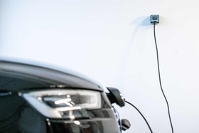 Avant de véhicule électrique Audi en recharge sur une prise witty de Hager montée sur un mur blanc dans un garage à domicile