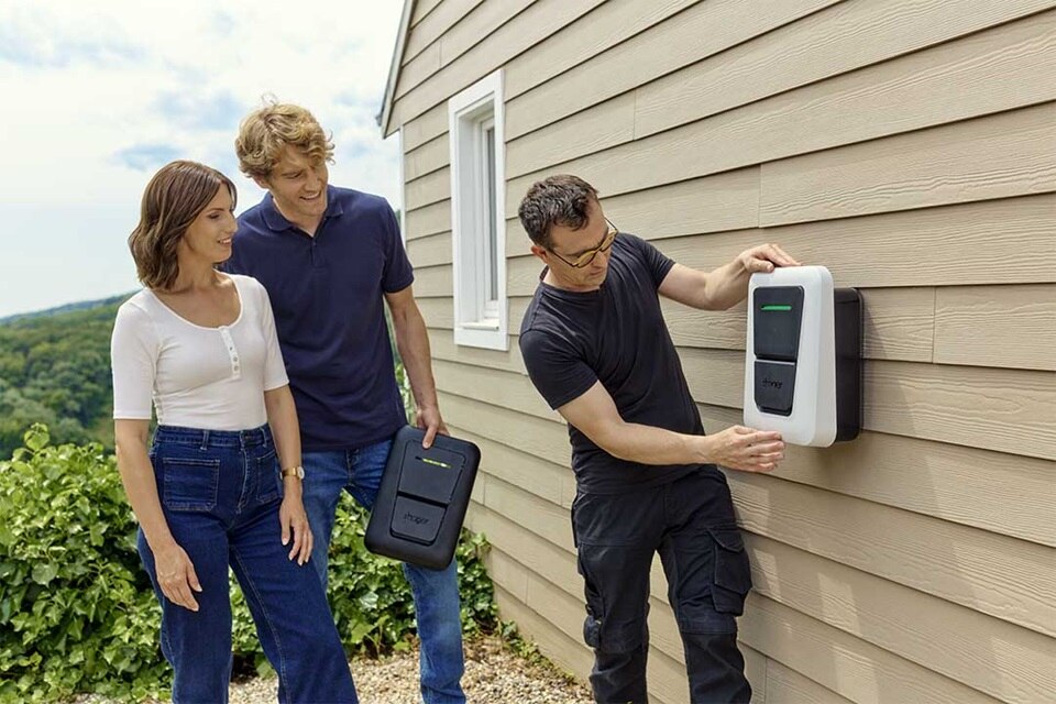 Couple et installateur IRVE qui choisissent la couleur du capot de leur borne witty one de Hager devant leur maison