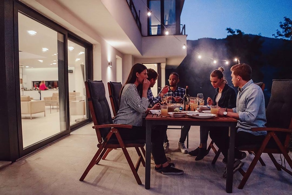 Groupe d'amis assis sur la terrasse illuminée en soirée