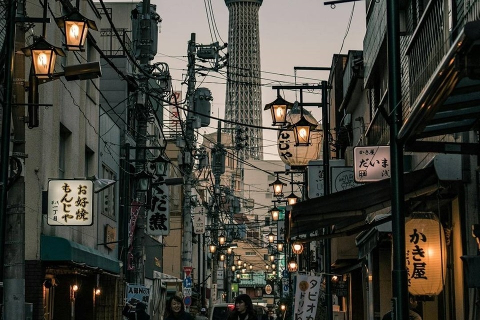 Rue de Tokyo au crépuscule avec lanternes et Tokyo Skytree en arrière-plan.