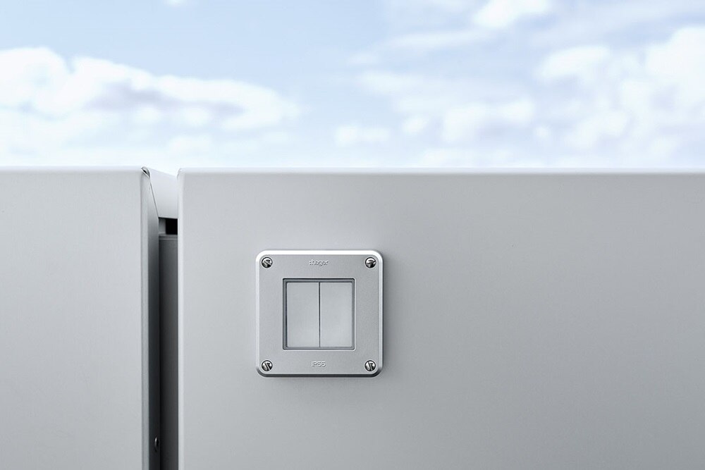 Hager Group Interrupteurs d'éclairage de la gamme kallysto et robusto sur une paroi en verre et un ciel bleu en arrière-plan